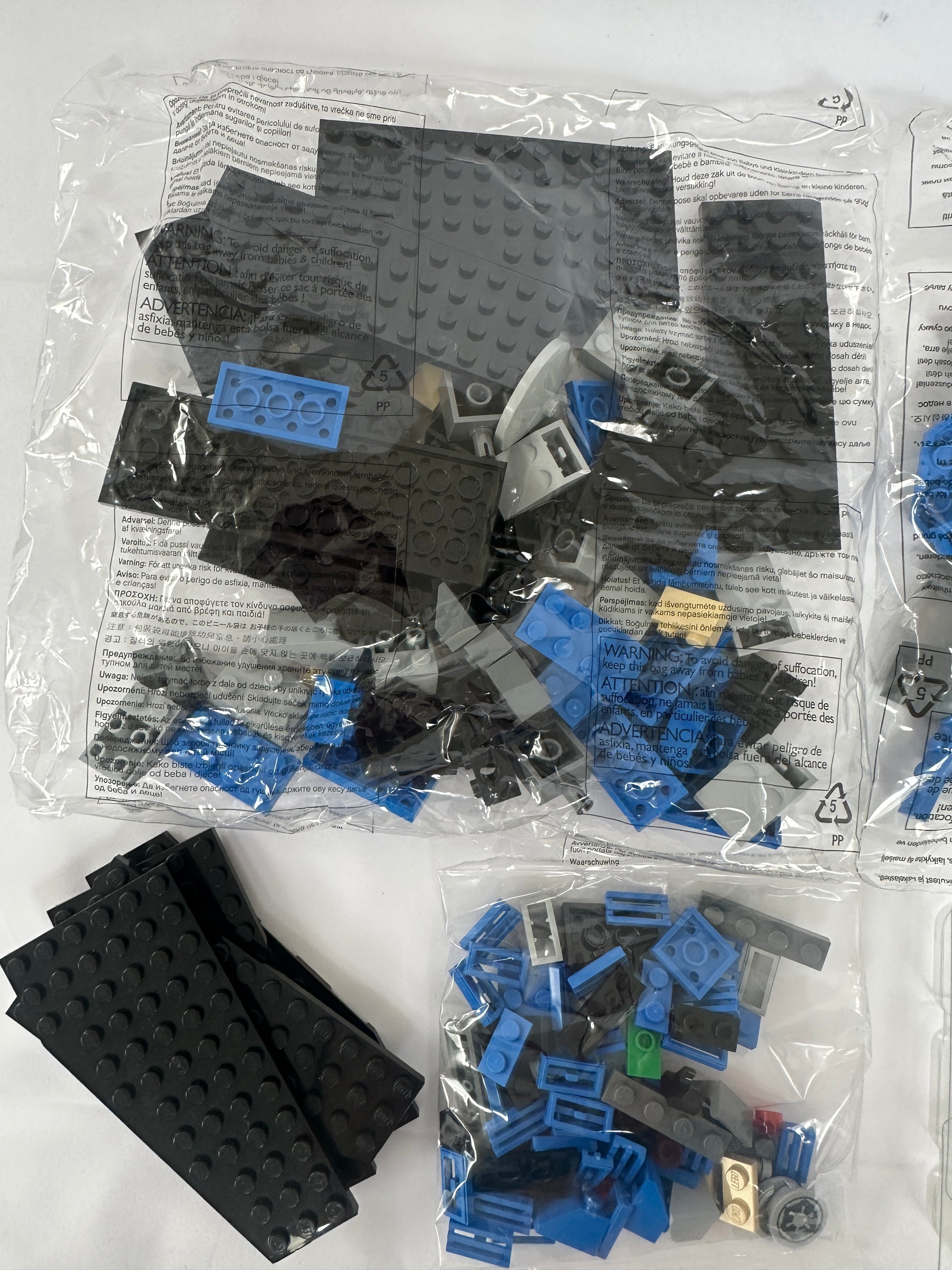 Assorted LEGO pieces including black and blue bricks on a white background