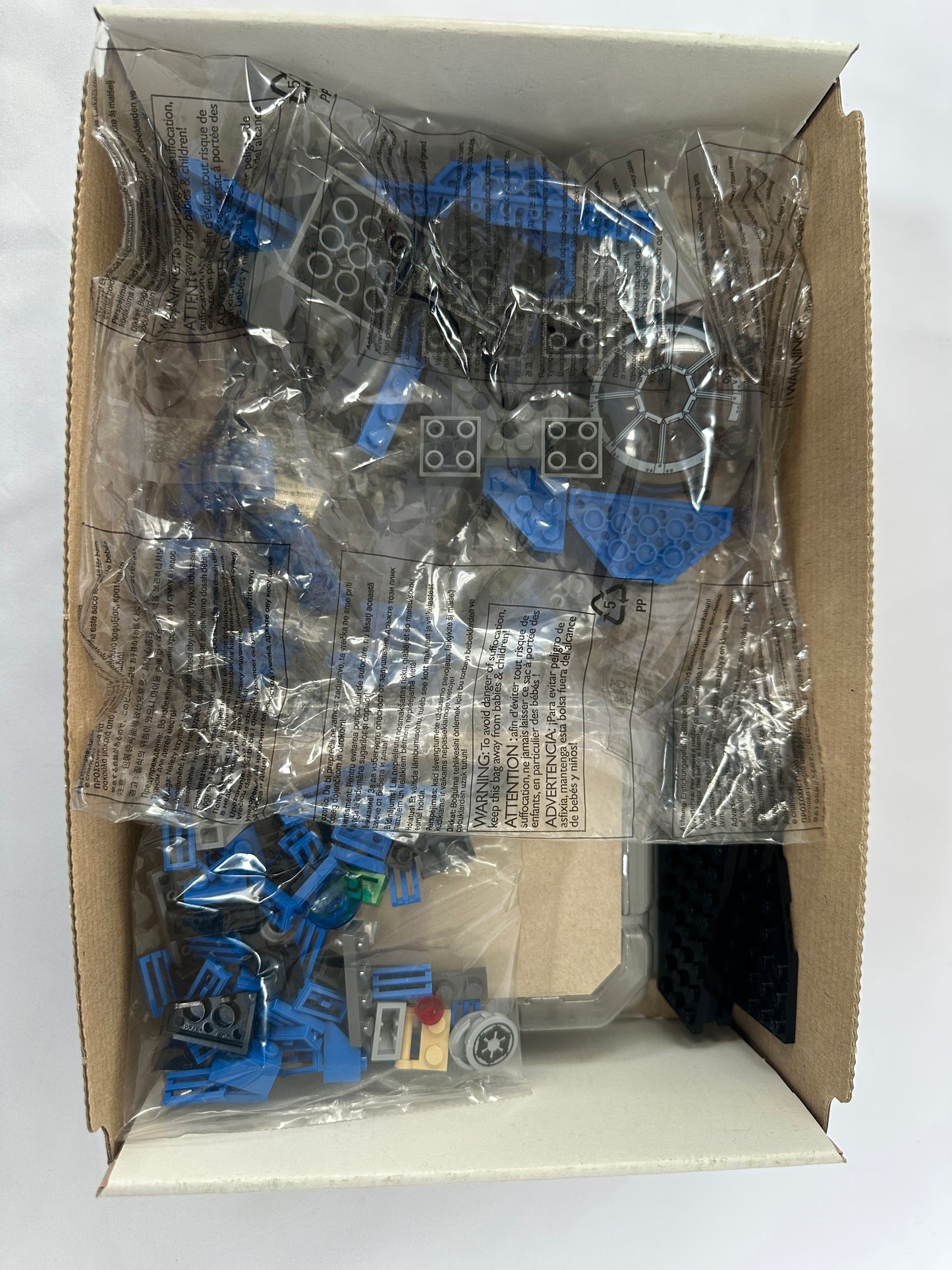 Box of Lego pieces with blue and gray components on a white background