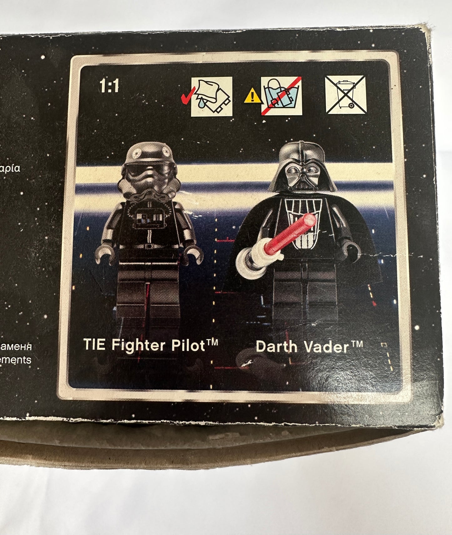 Box with TIE Fighter Pilot and Darth Vader figures on a space-themed background