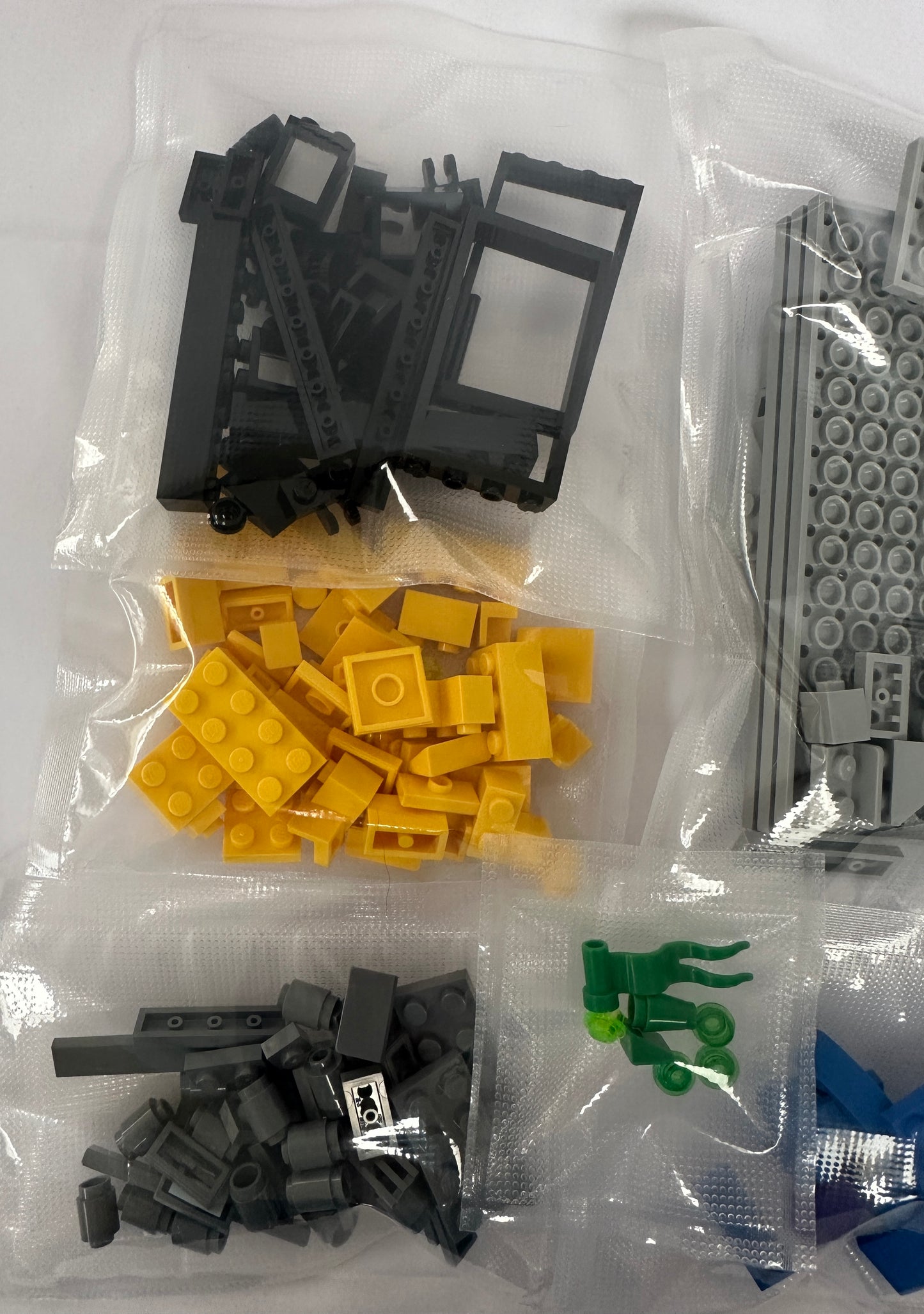 Assorted building blocks including black, yellow, and gray pieces in clear plastic bags on a white background.