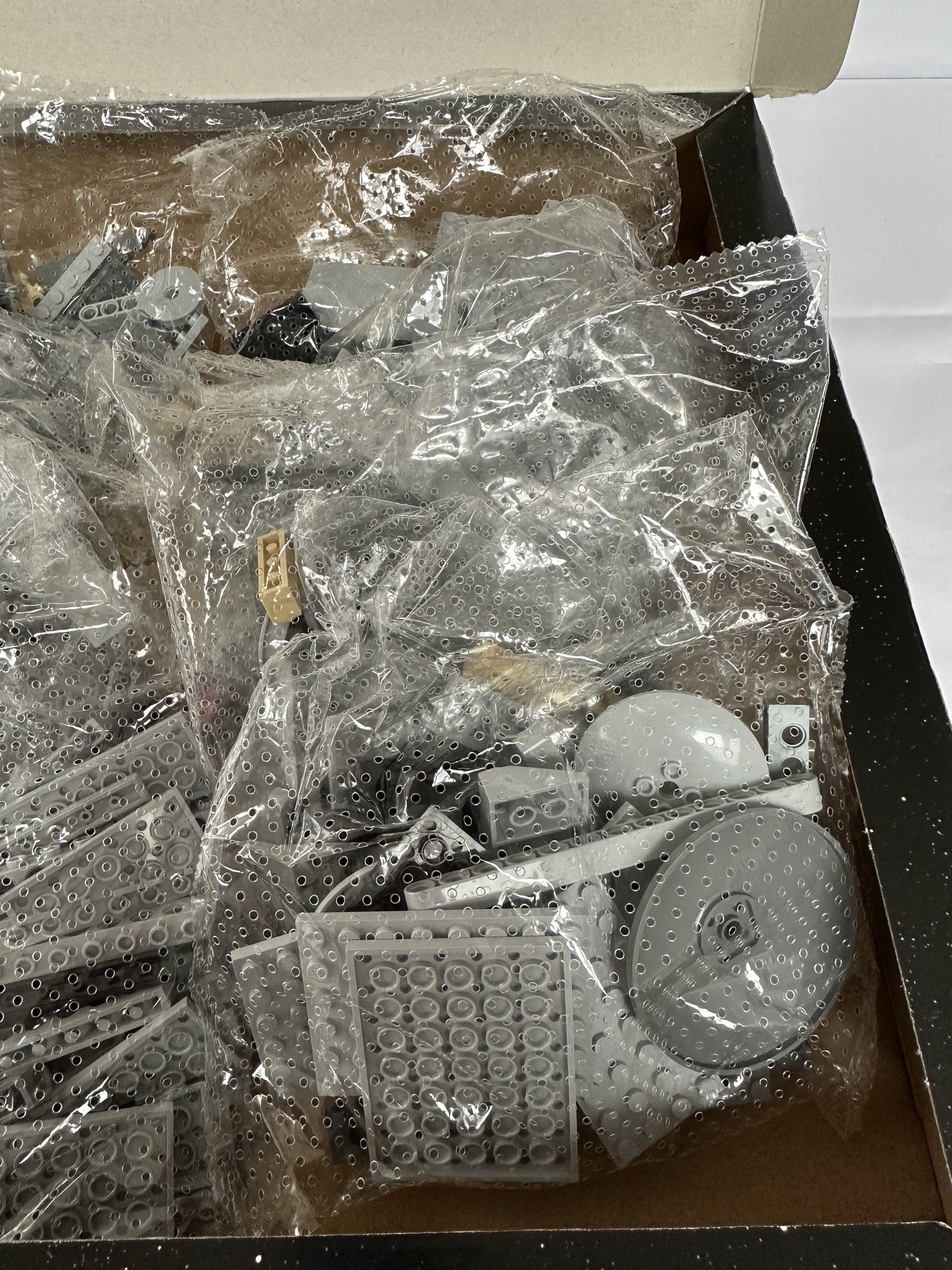 Box of assorted gray building blocks with clear plastic packaging.