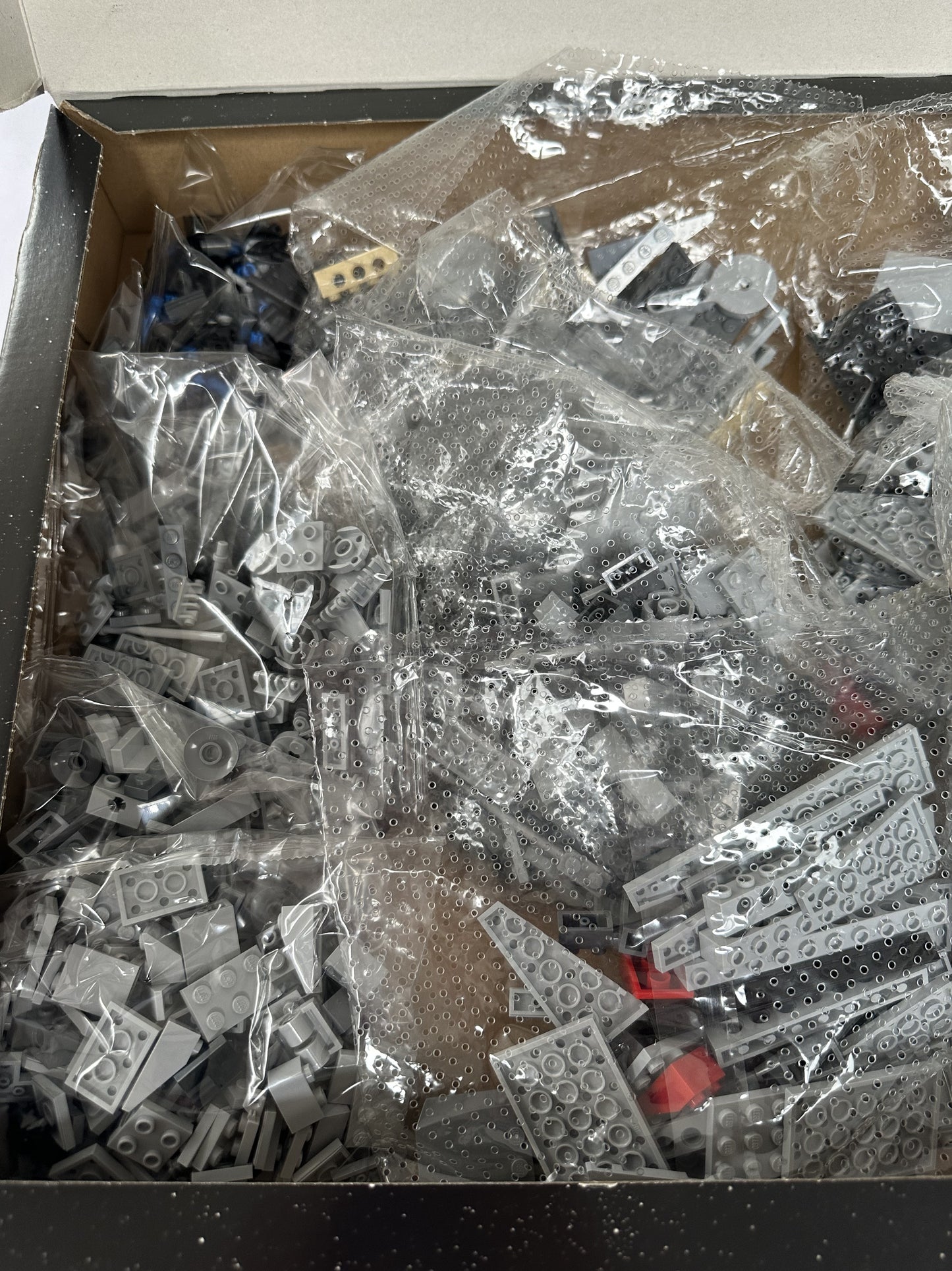 Box of assorted plastic building blocks with clear plastic packaging.