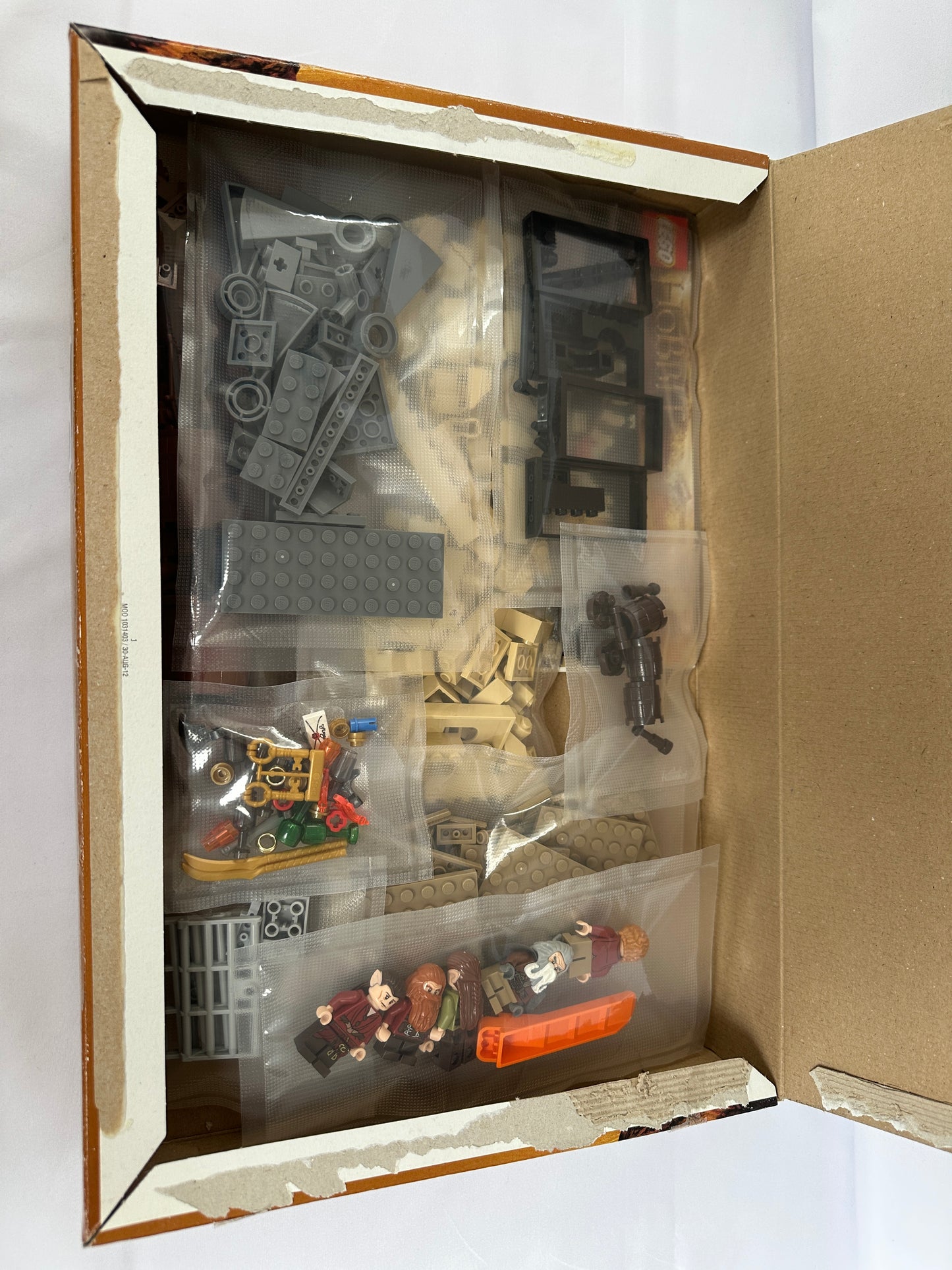 Open box containing miniature model parts on a white background
