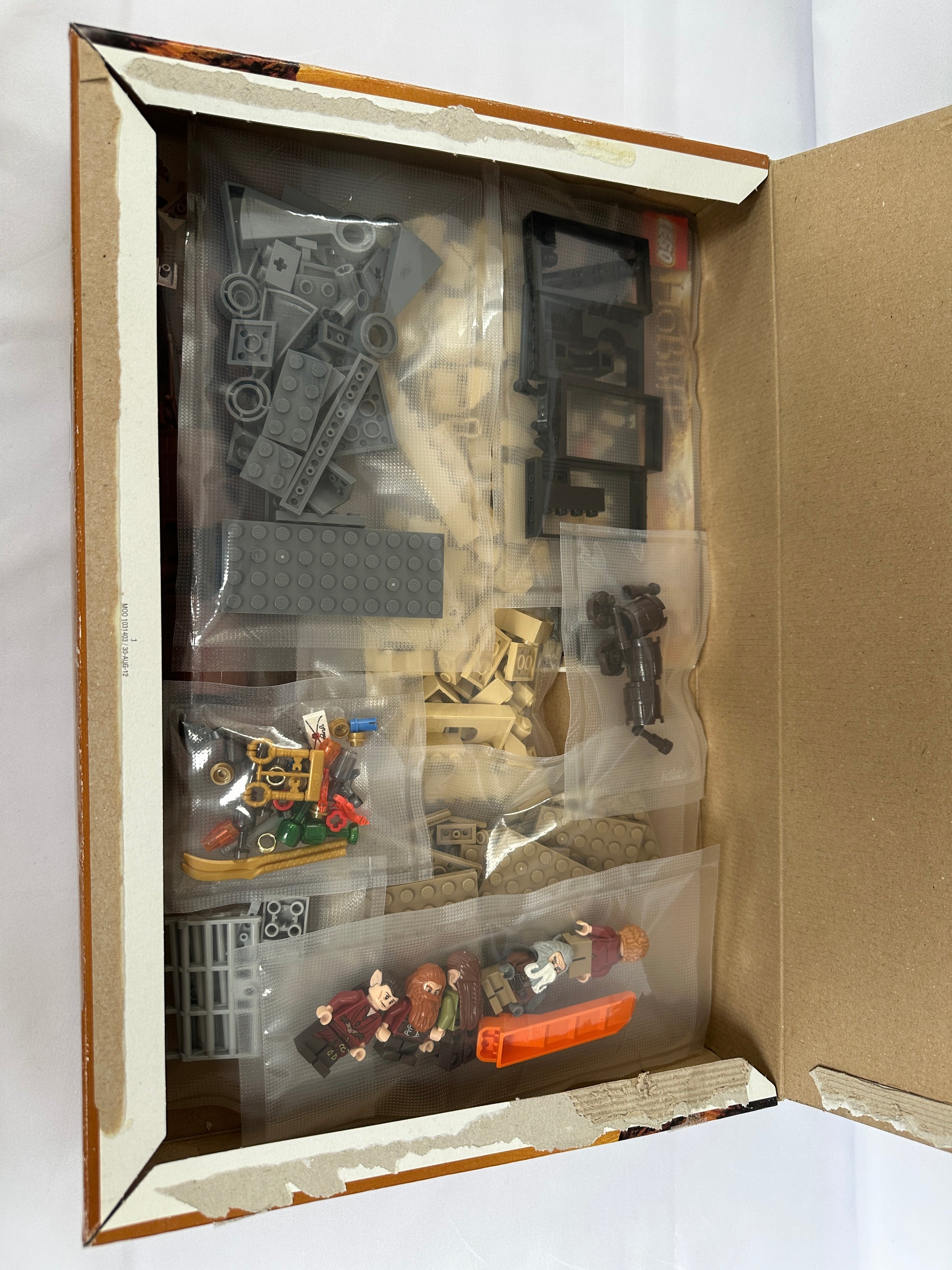 Open box containing miniature model parts on a white background