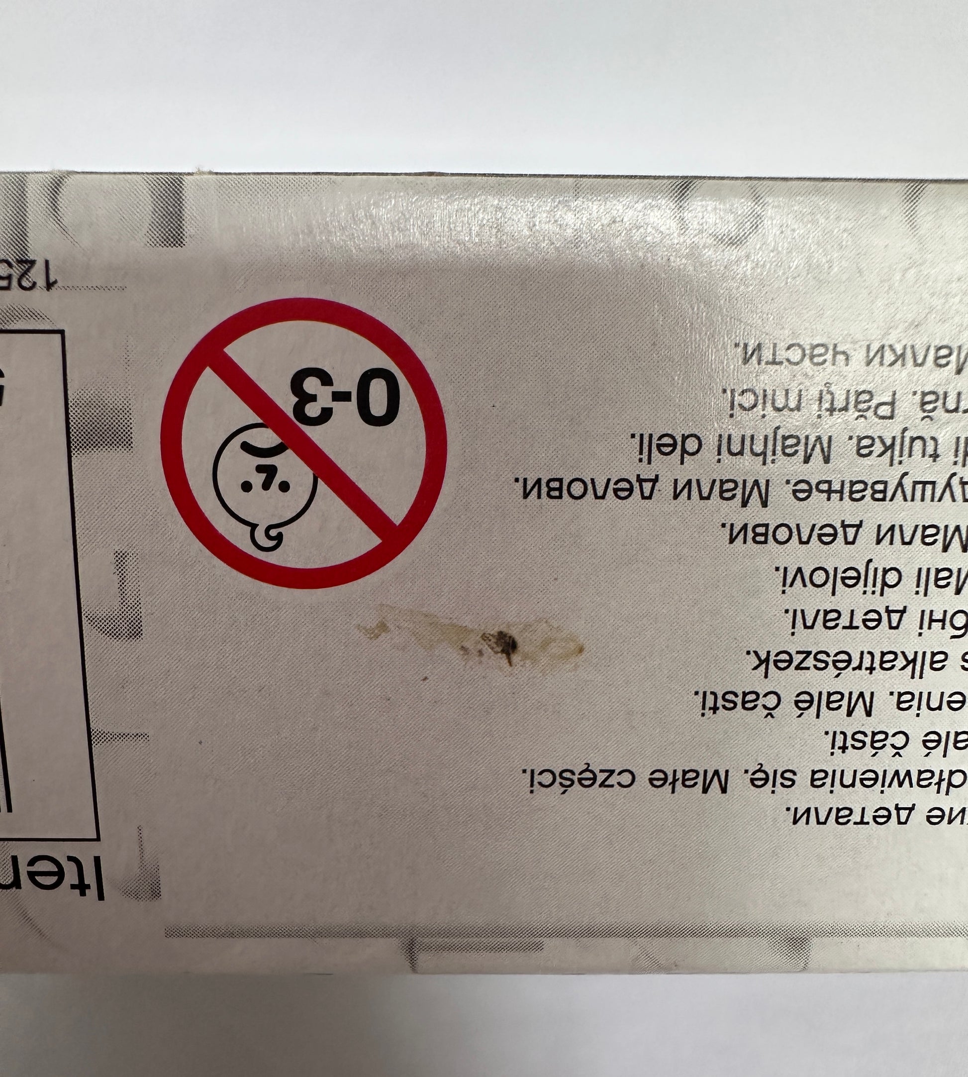 Product packaging with a warning symbol and text, showing signs of wear.