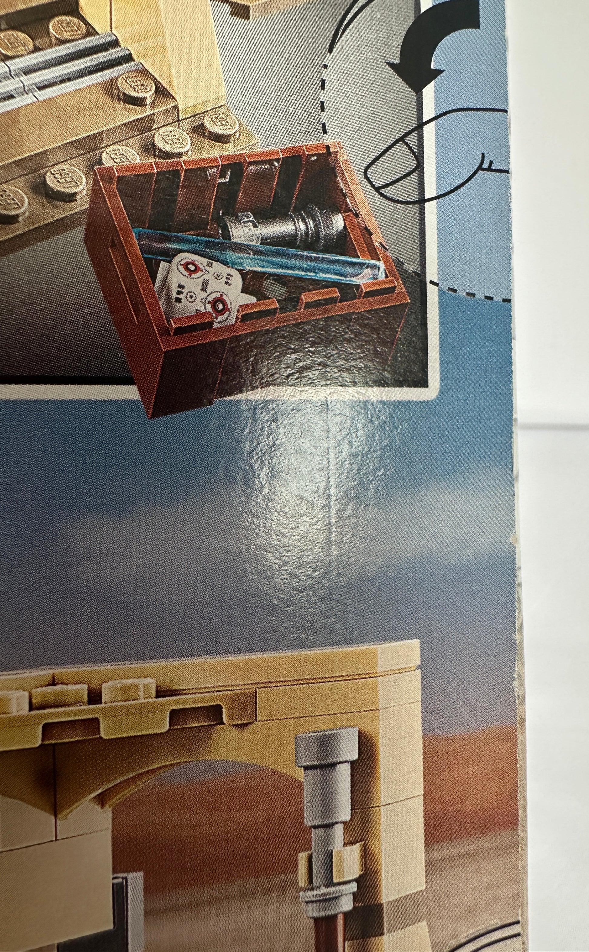 Close-up of a detailed model with a small box containing tools on a metallic surface.