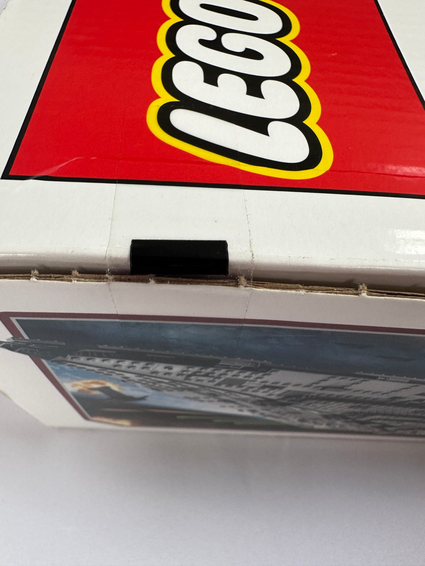 Close-up of a LEGO logo on a red background with a blurred poster in the foreground.
