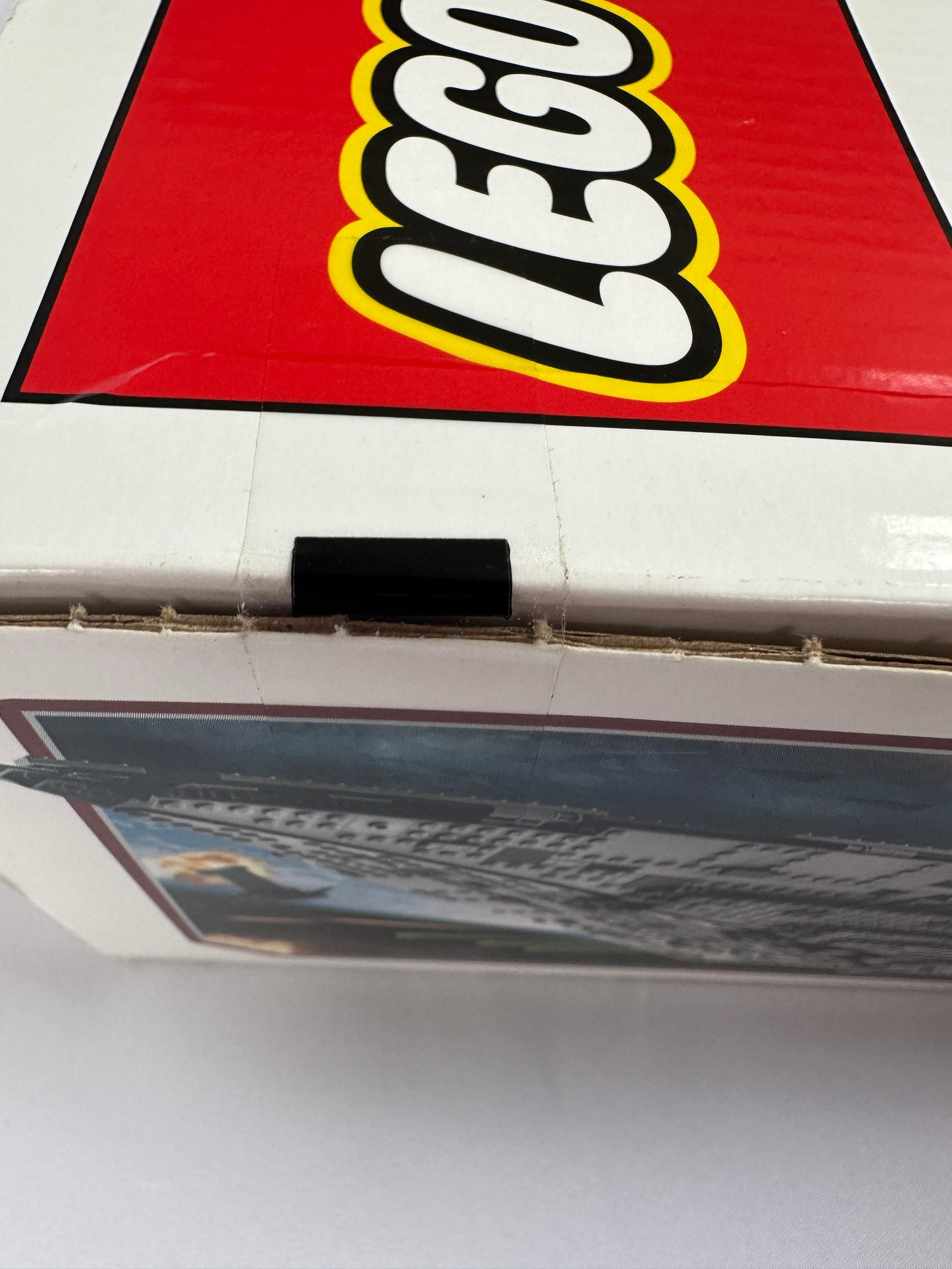 Close-up of a LEGO logo on a red background with a blurred poster in the foreground.