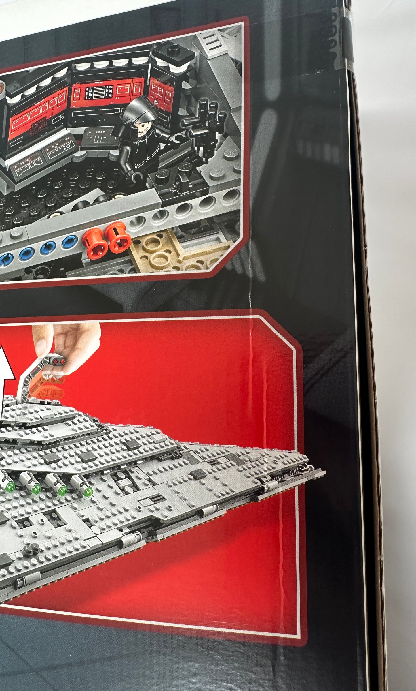Close-up of a LEGO set packaging with building pieces and a hand holding a tool.