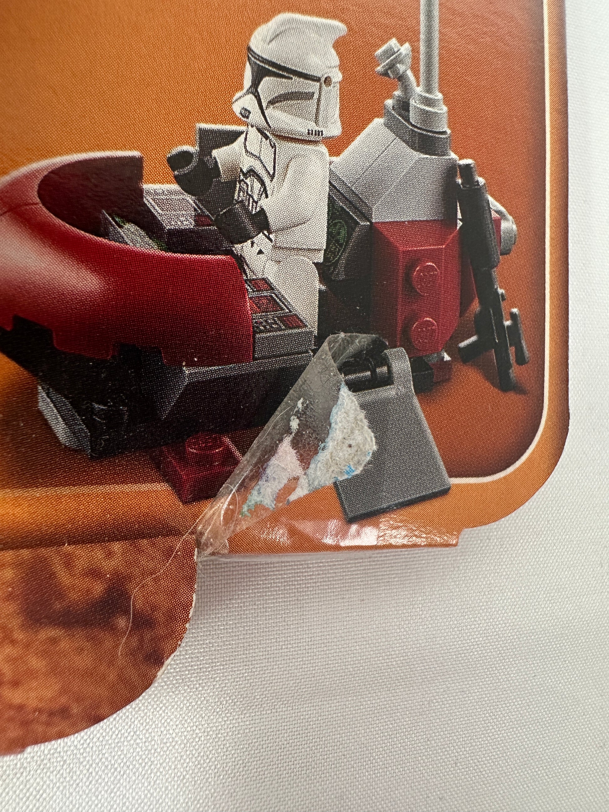 Close-up of a toy robot figure on a brown surface with a white background